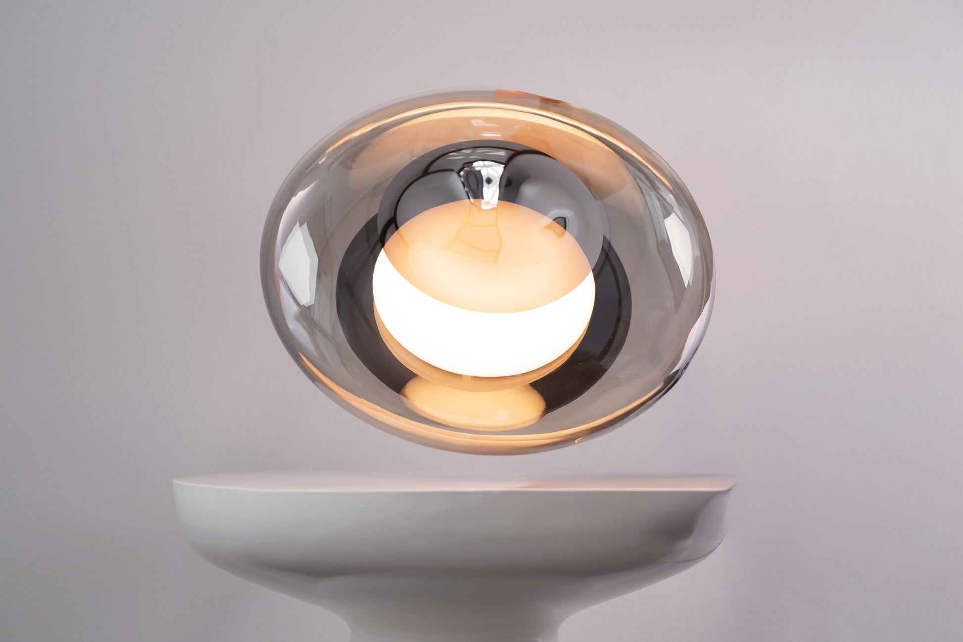 Modern wall-mounted light fixture with a glass cover on a gray background