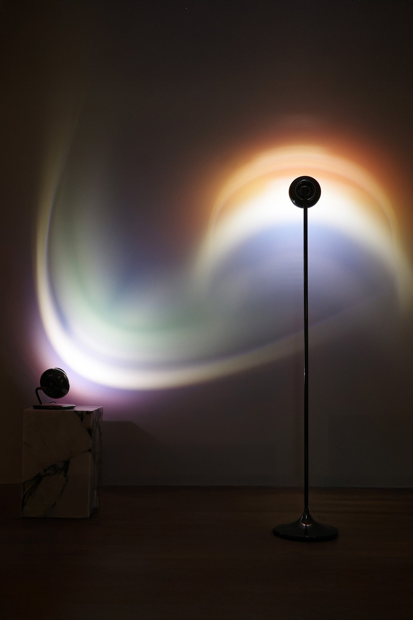 A portable table lamp with a black spherical body and a rotating base, displayed against a neutral background.