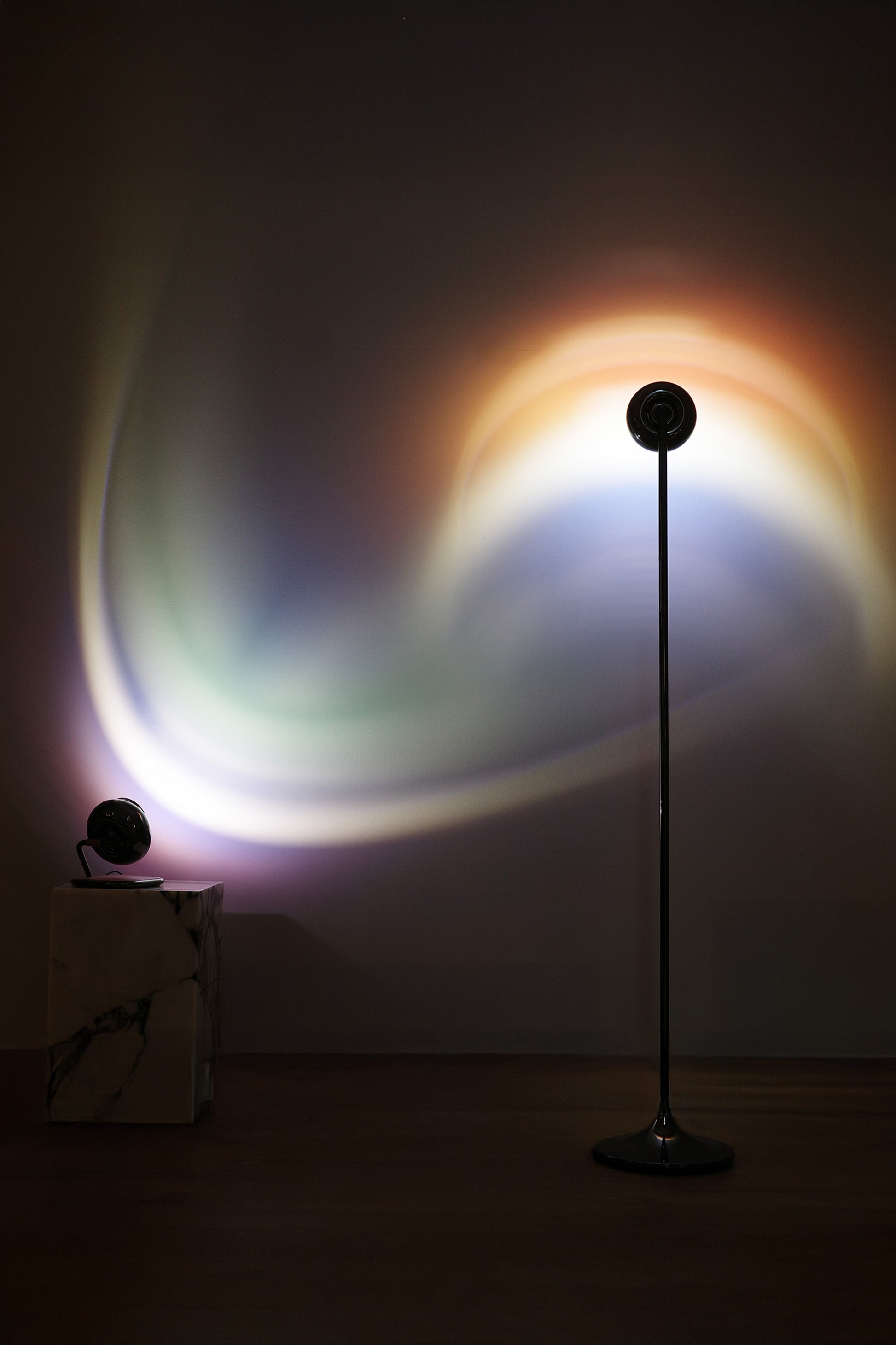 A portable table lamp with a black spherical body and a rotating base, displayed against a neutral background.