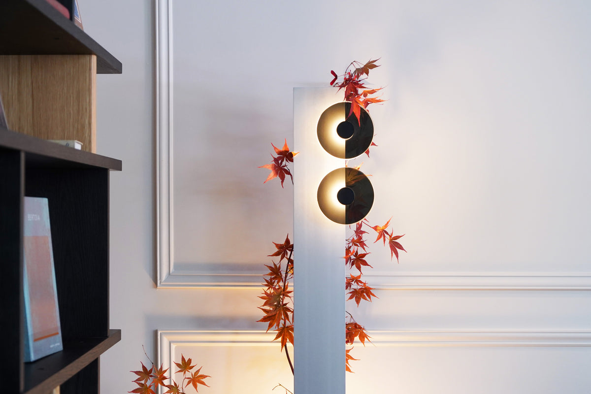 Decorative wall sconce with yin yang design and leaves on a white wall.