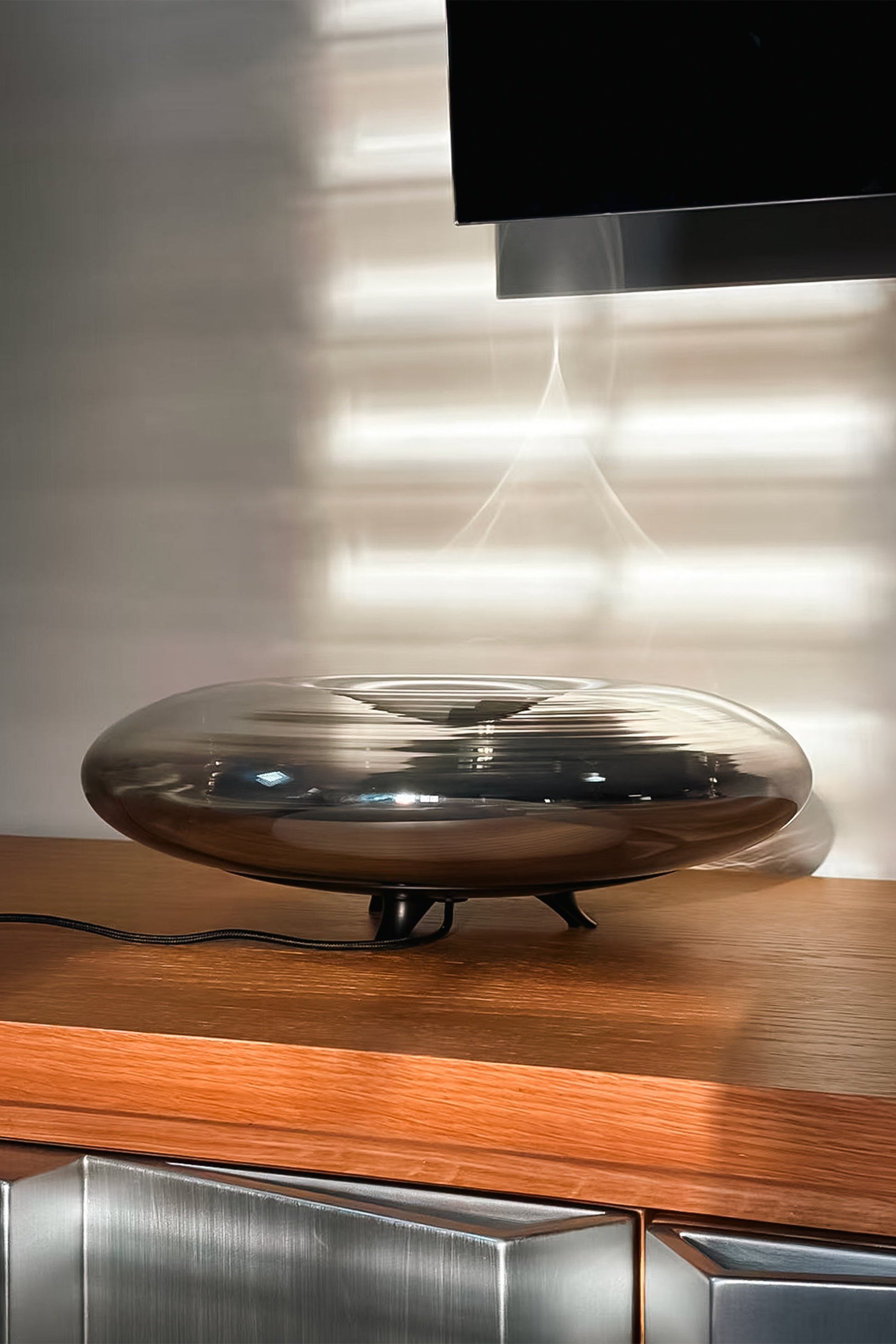 Modern metallic lamp on a wooden surface with a reflective wall in the background