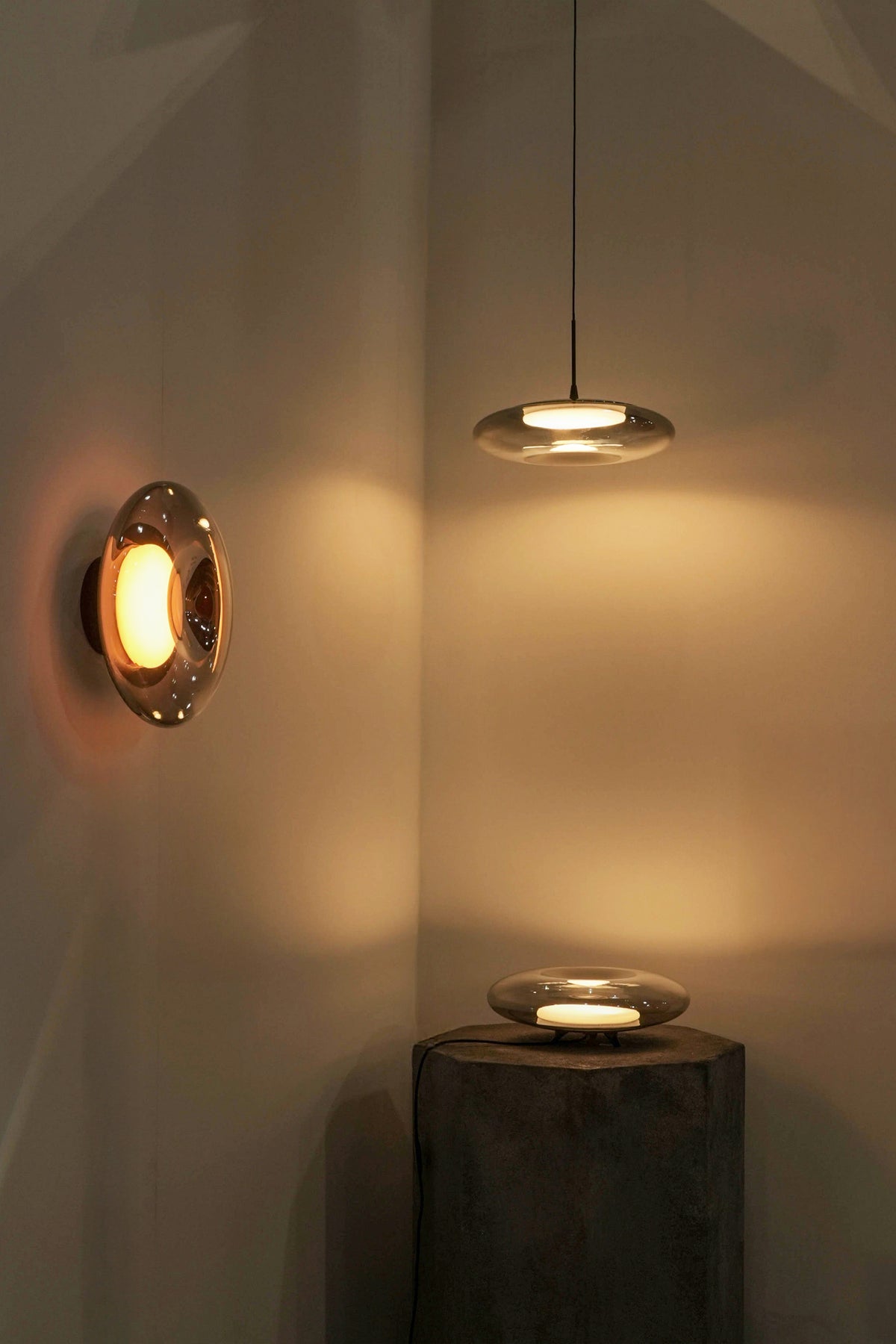 Modern wall and ceiling lights casting warm glow on a neutral wall.
