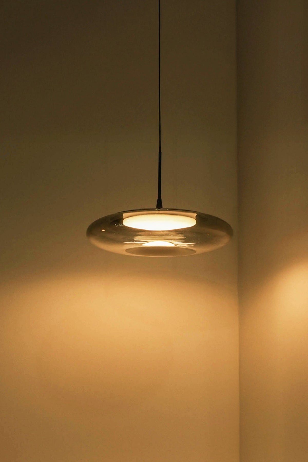 Pendant light fixture casting a warm glow on a wall.