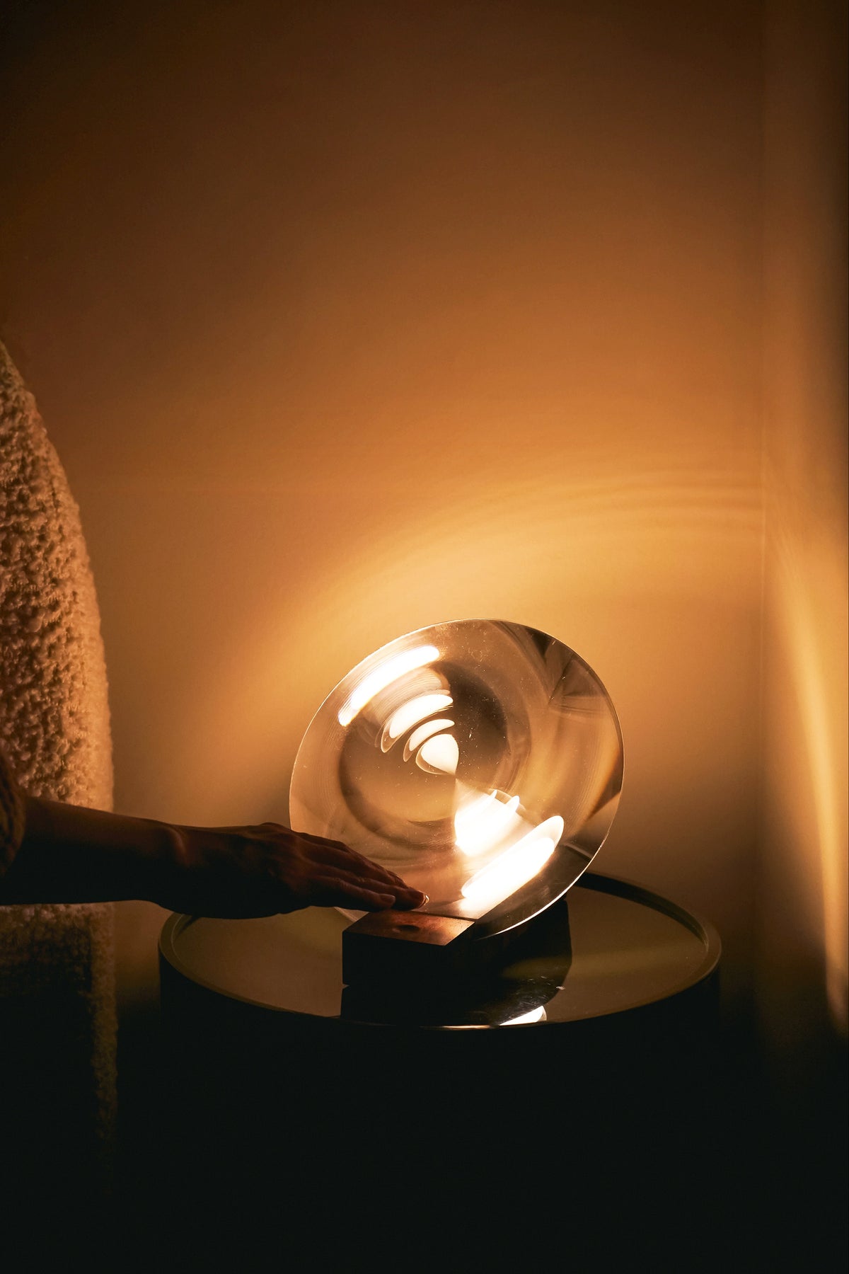 Person touching a glowing lamp in a dimly lit room