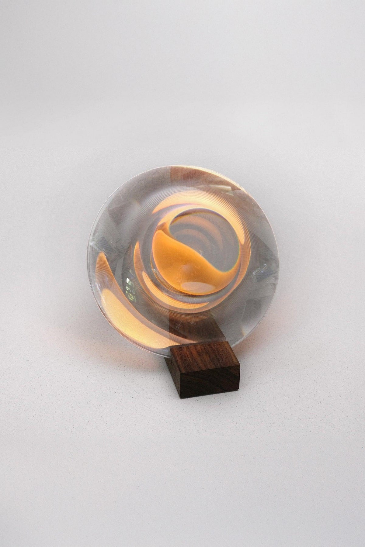 Clear glass object with a wooden base on a white background