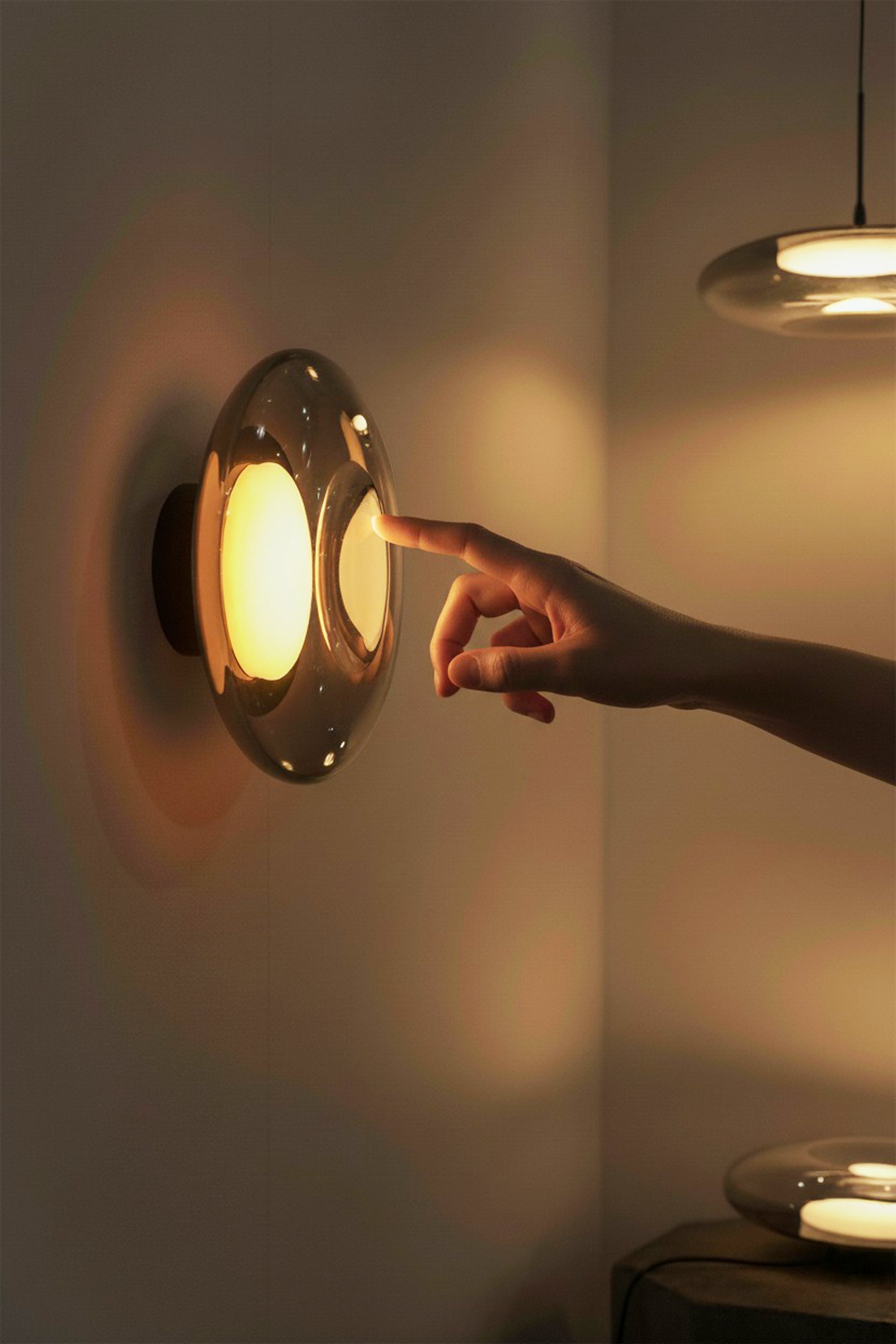 Hand touching a wall-mounted light fixture in a dimly lit room