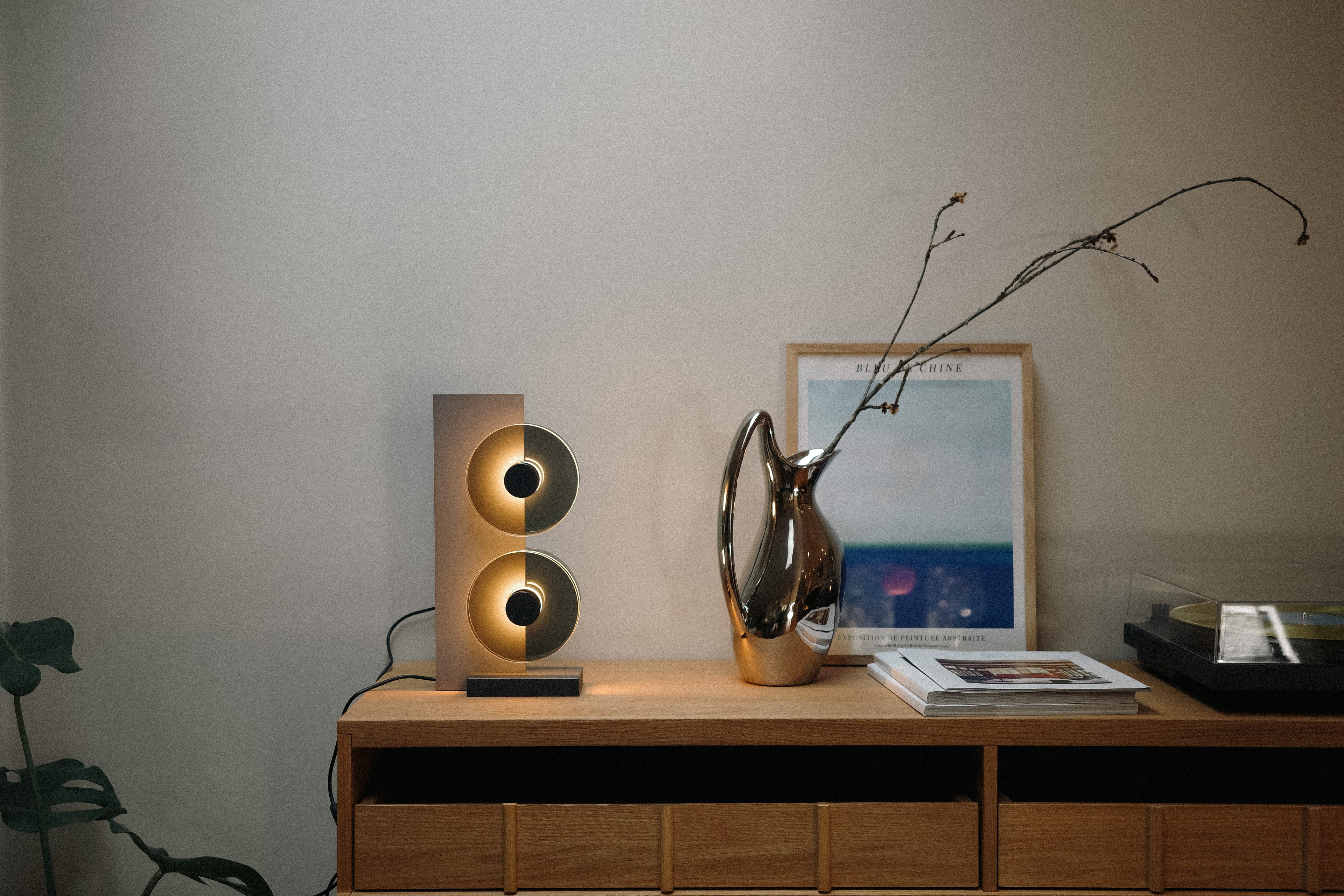 Modern interior with a wooden console table featuring decorative items including a lamp, vase, and framed picture.