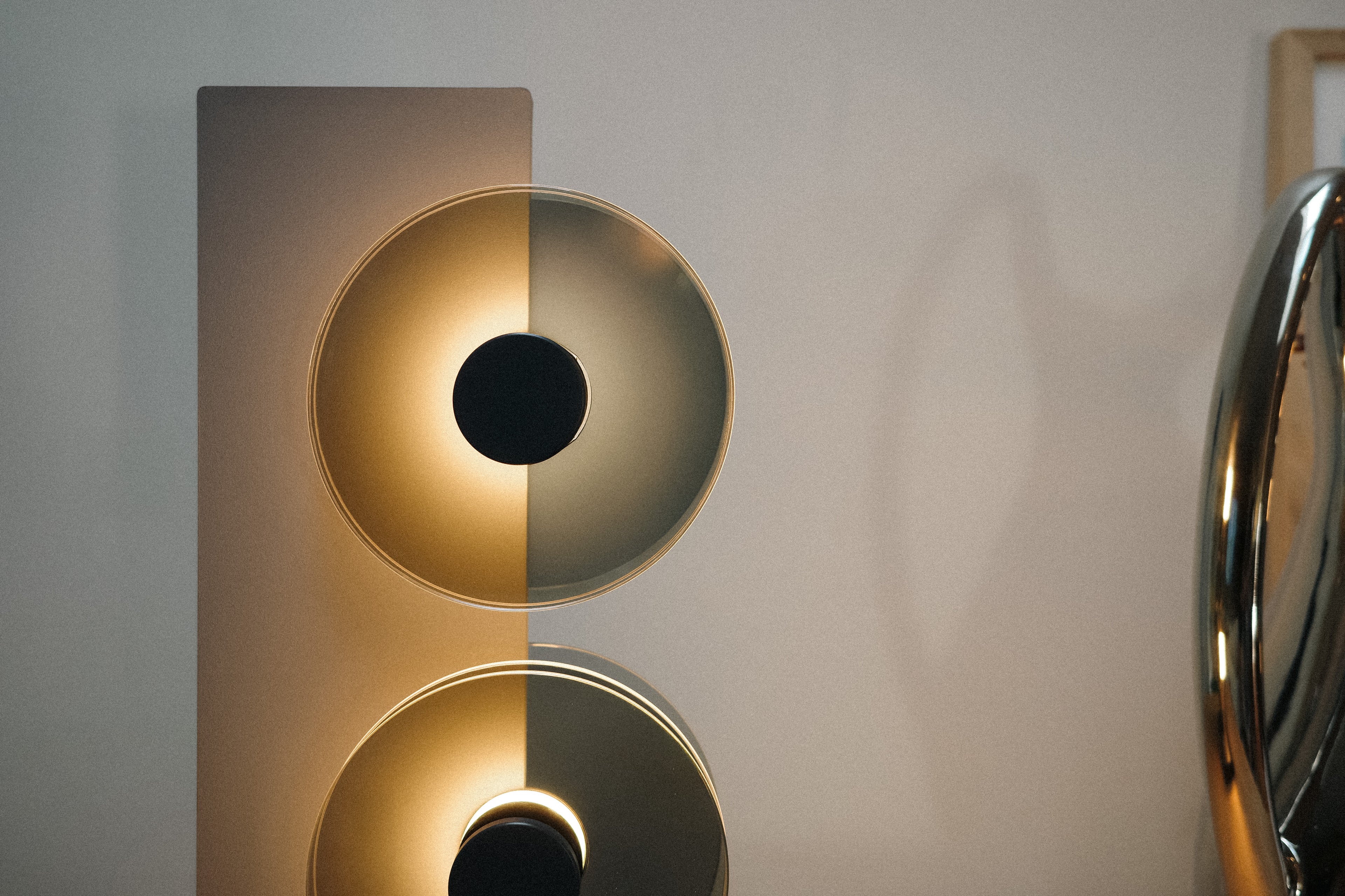 Modern wall-mounted light fixture with a metallic finish on a neutral background