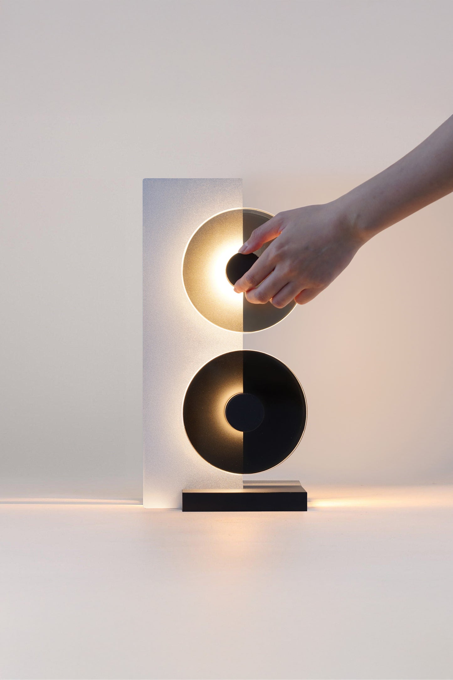 Modern wall sconce with a hand interacting with it on a plain background