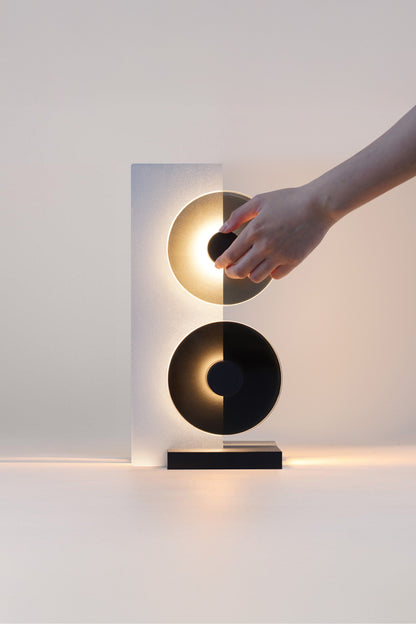 Modern wall sconce with a hand interacting with it on a plain background