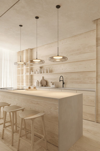 Modern kitchen with wooden island, stools, and pendant lights.