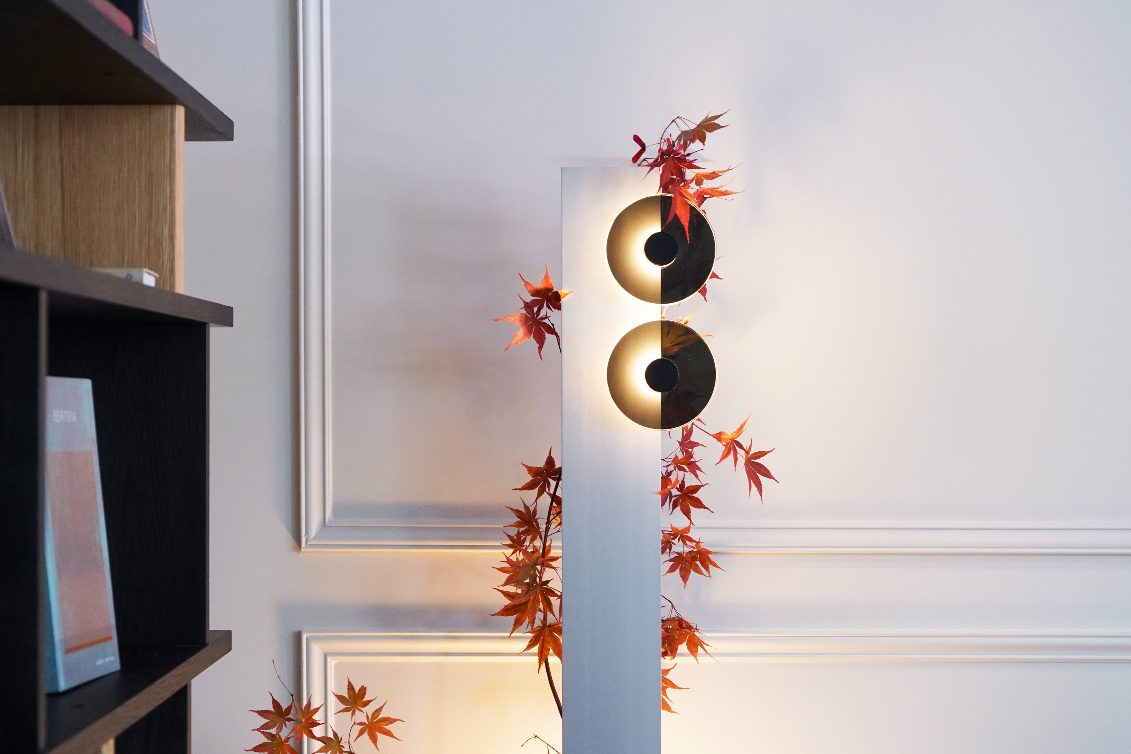 Decorative wall sconce with yin yang design and leaves on a white wall.