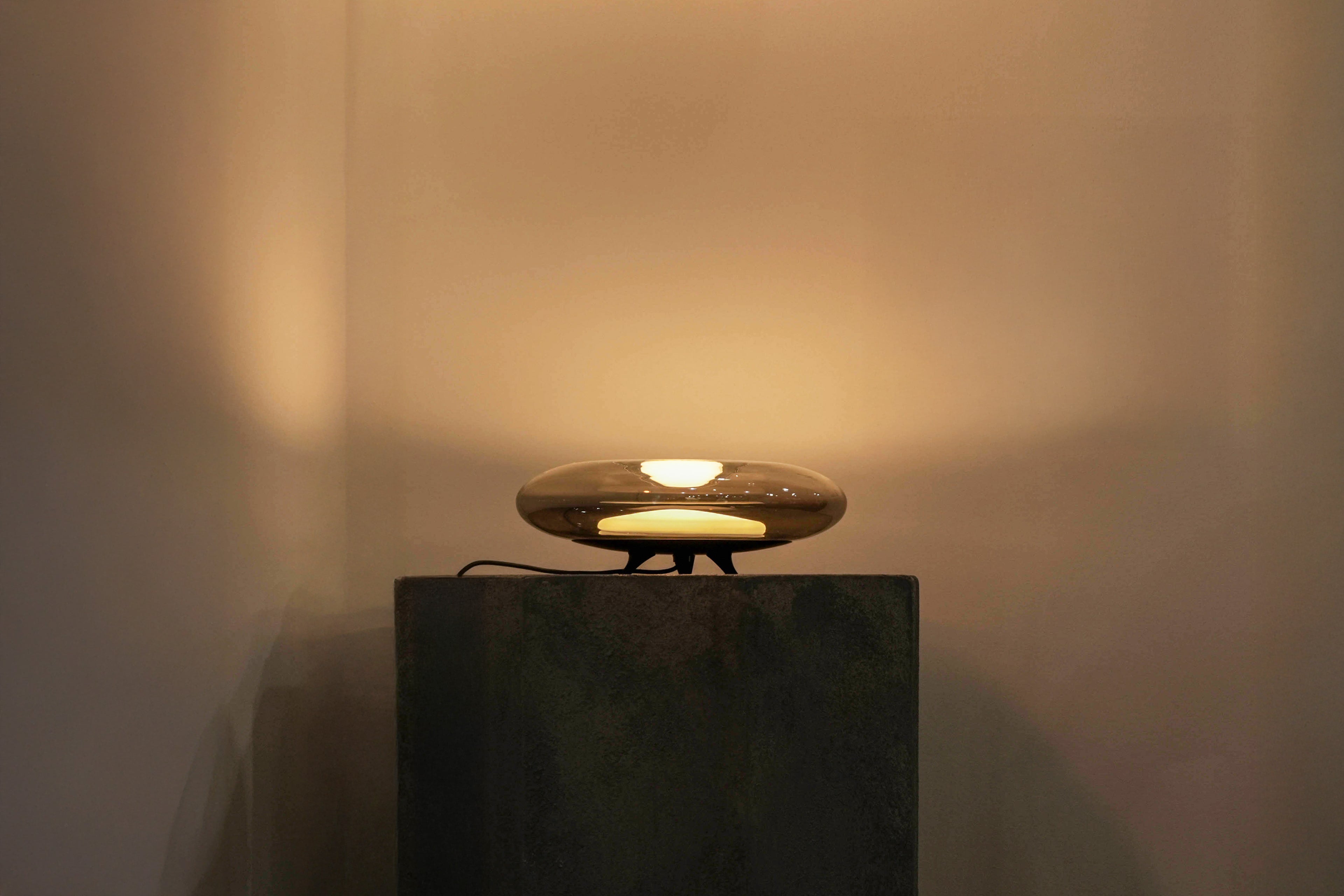 Round lamp on a dark pedestal against a beige wall