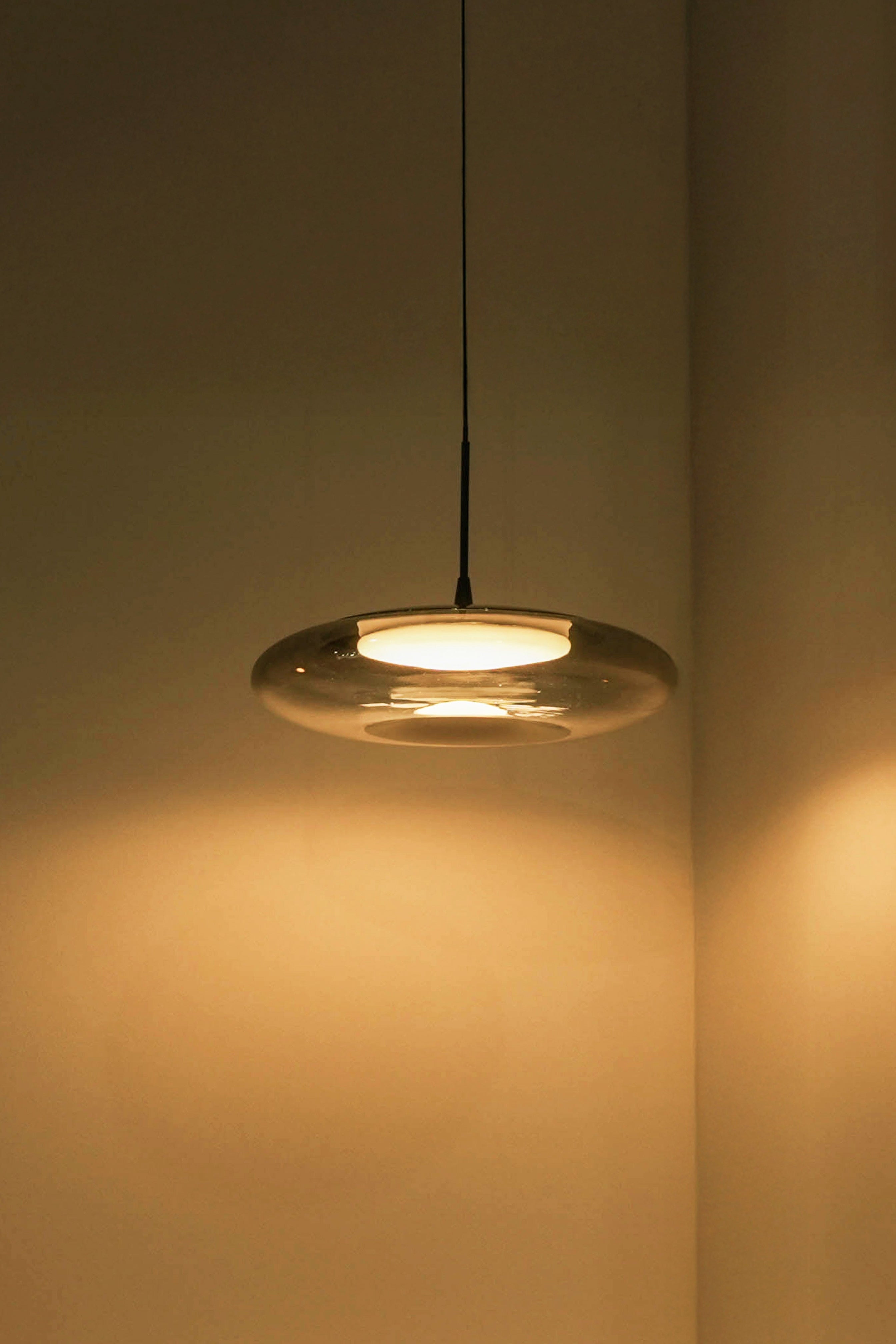 Pendant light fixture casting a warm glow on a wall.