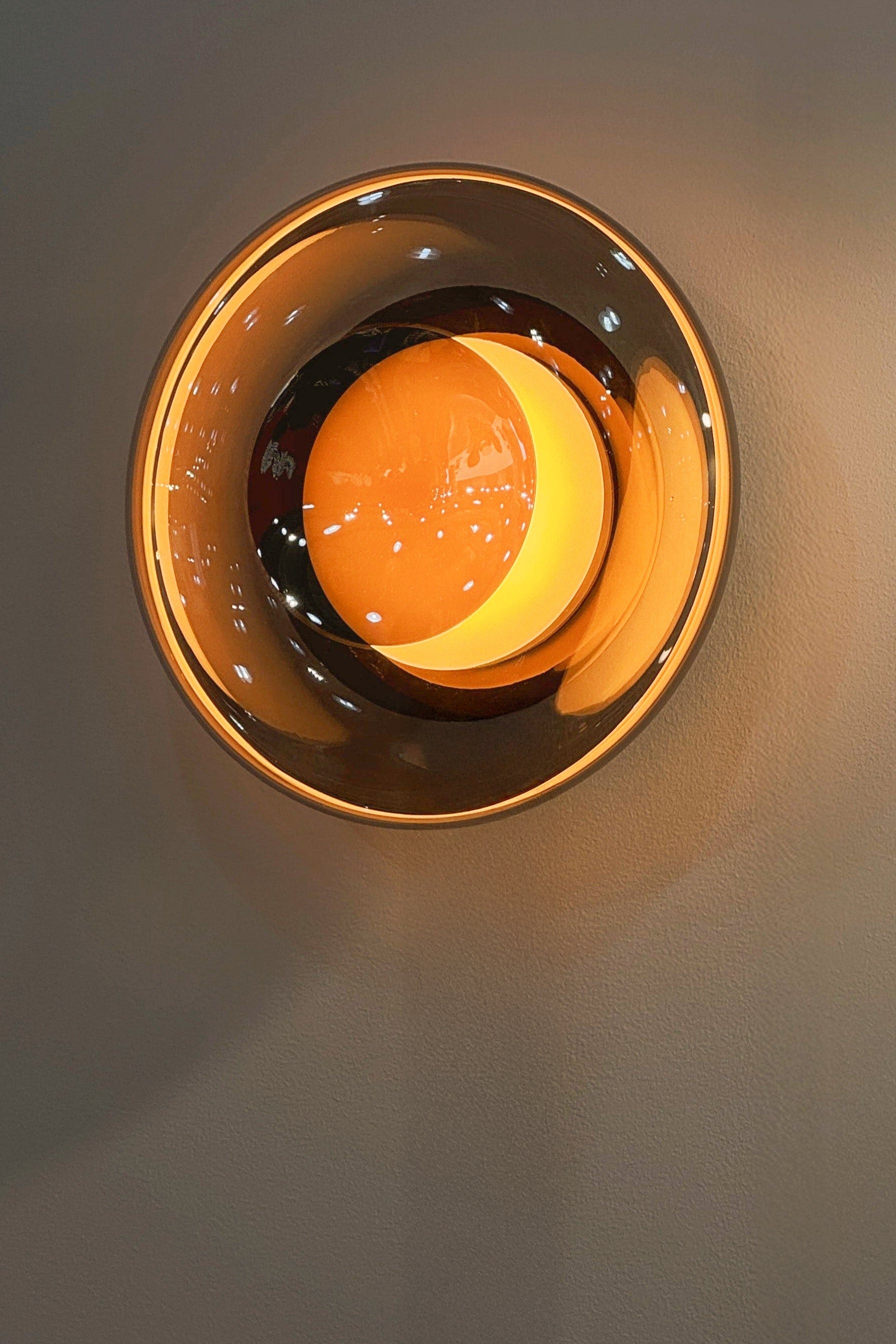 Round light fixture with a gold rim on a beige wall