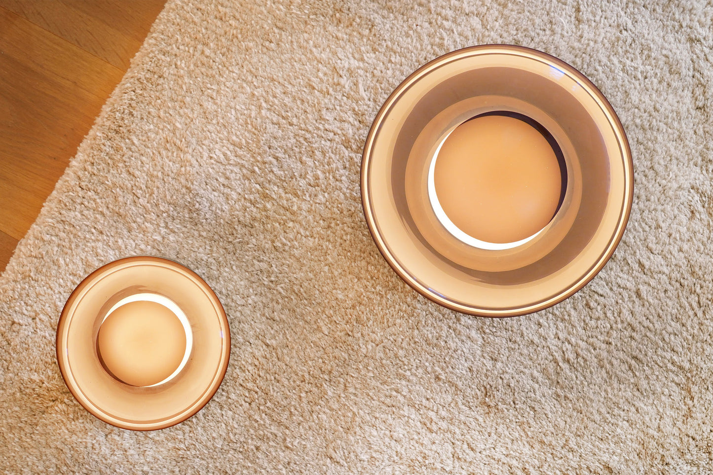 Two gold bowls on a textured beige surface