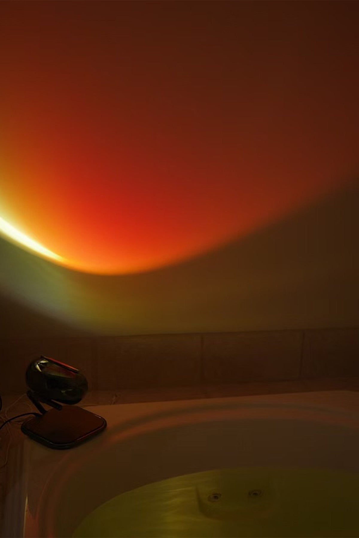 Orange light casting a shadow on a white wall with a camera on a tripod in the foreground.