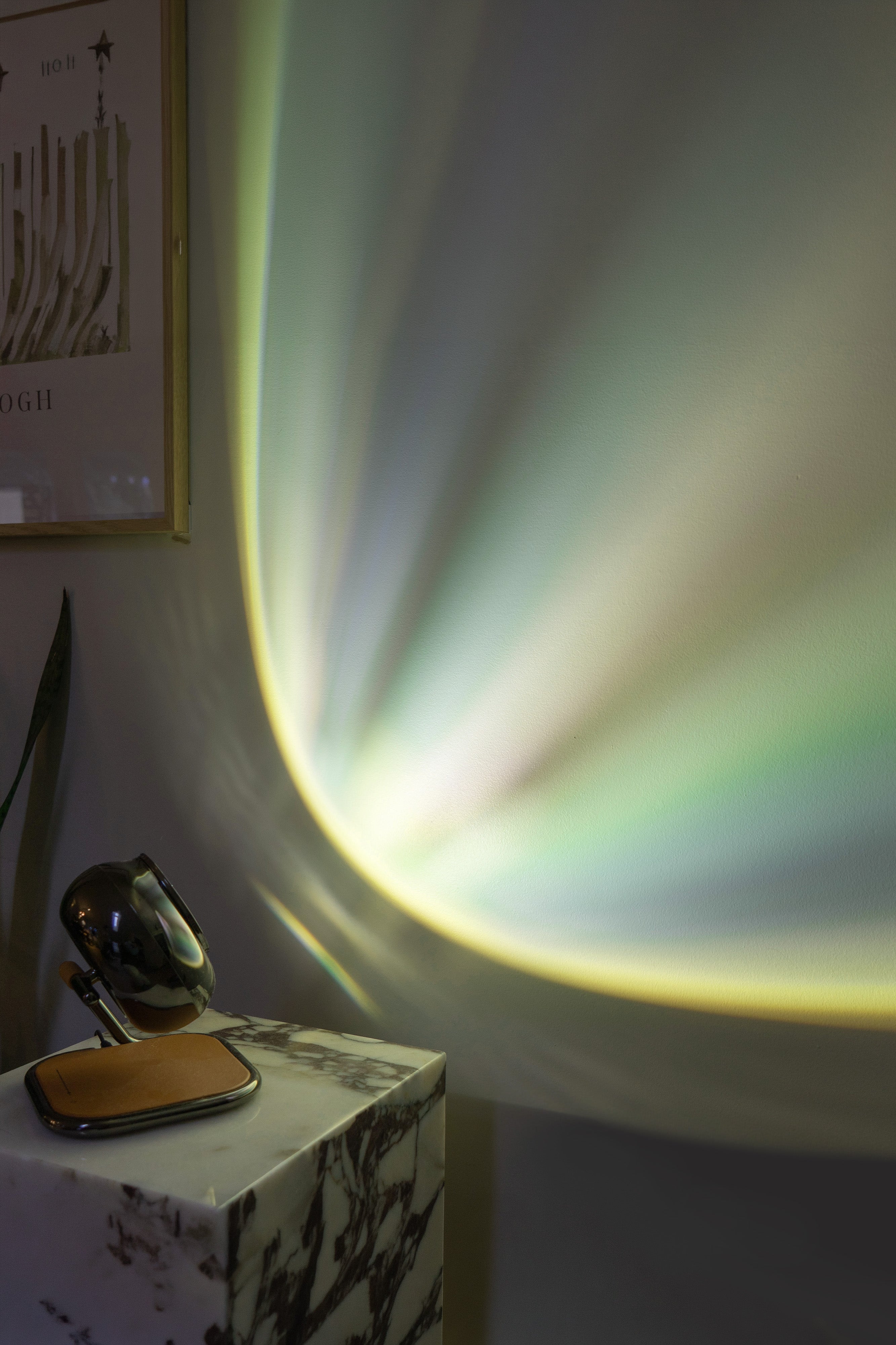Light projection on a wall with a small table and mirror in the foreground.